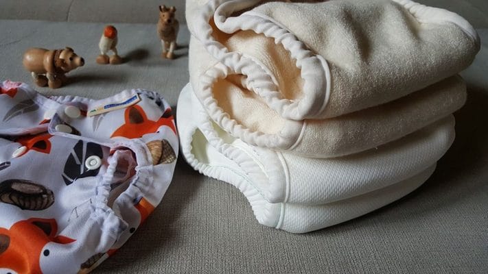 Hibridni sistem Mother ease Wizard Duo ... univerzalno velike nepremočljive hlačke na levi ter kupček različnih vložkov na desni - od spodaj navzgor si sledijo: stay dry nočni, stay dry, bombaž in bambus.